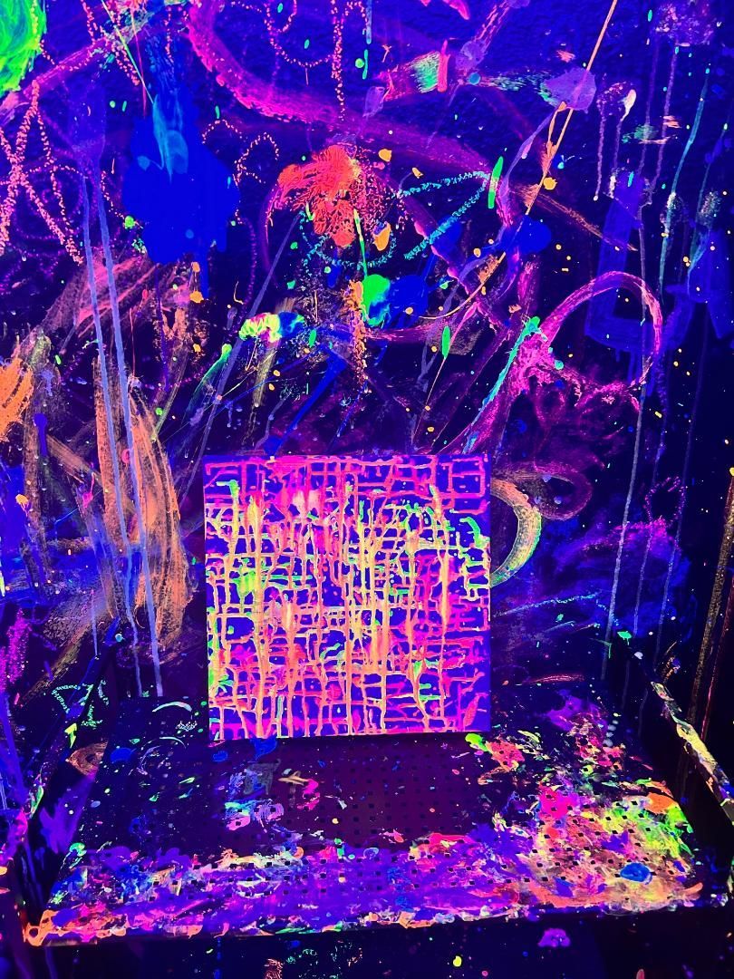Neon abstract painting with a brightly colored grid-like square at the center on a dark, paint-splattered background