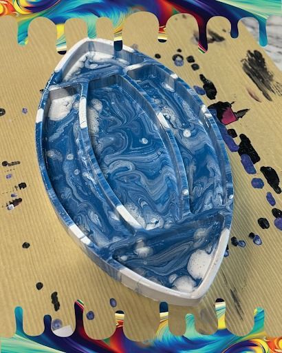 Blue oval soap on a textured yellow surface with colorful paint splashes around it
