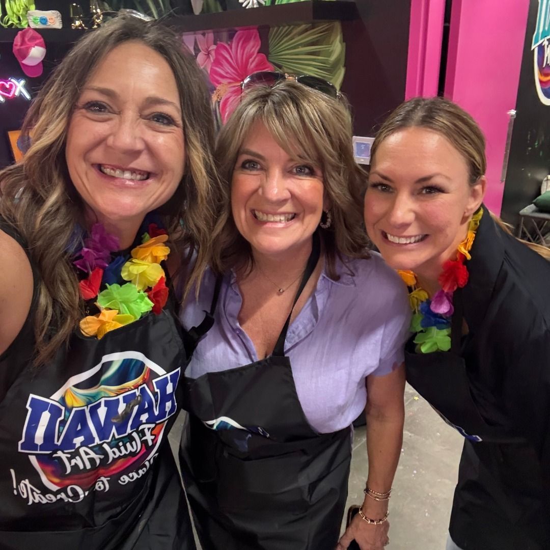 Three smiling people in leis posing for a photo at a colorful party event