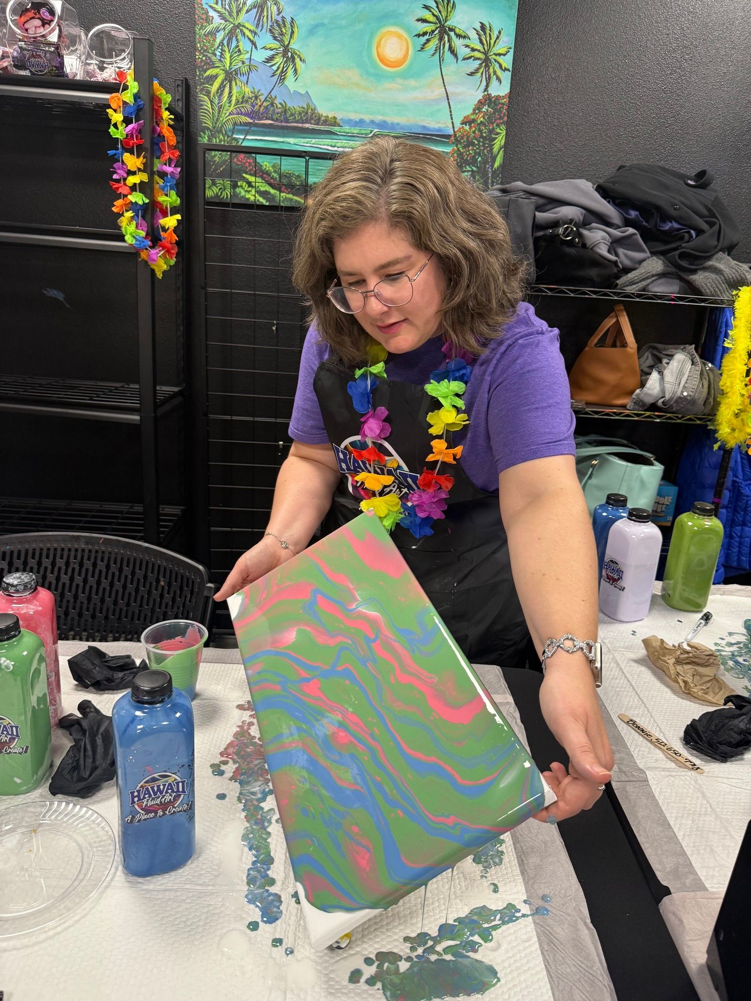 Woman displaying a colorful marbled painting at a craft table indoors