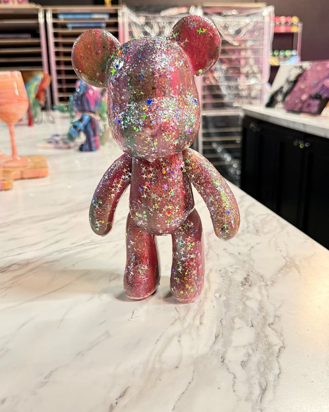 Glittery pink bear figurine standing on a marble table in a store display