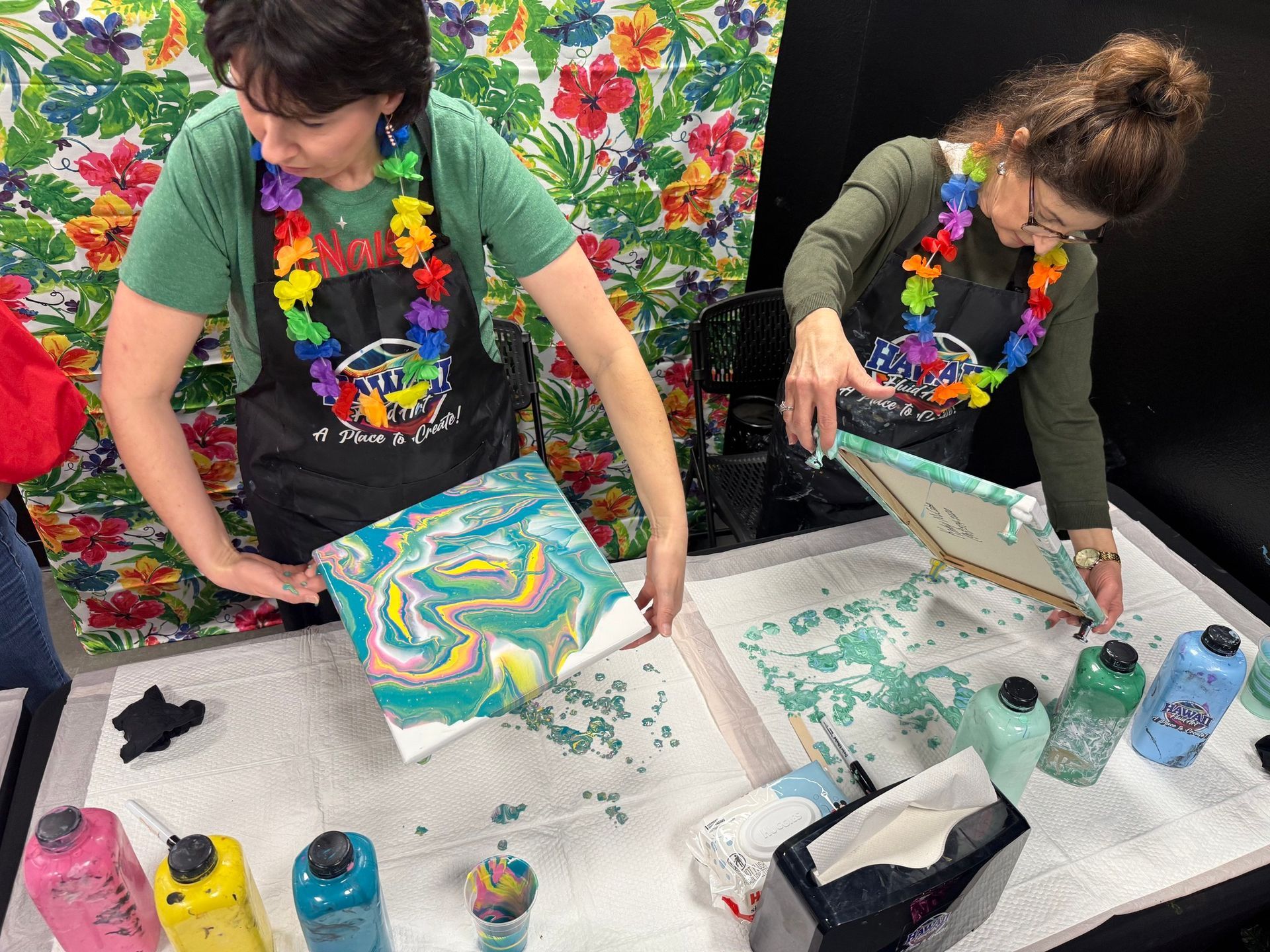 Person screen printing colorful fabric prints at a worktable with paint and supplies