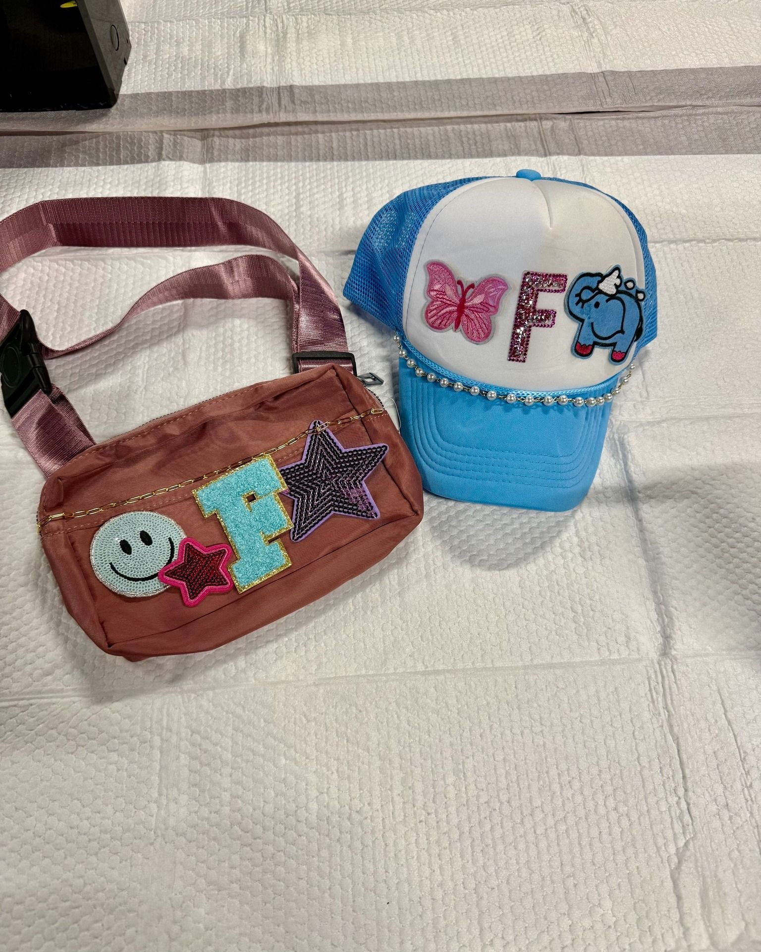 Two small beaded accessories: a brown shoulder bag and a blue-and-white cap with colorful letters.