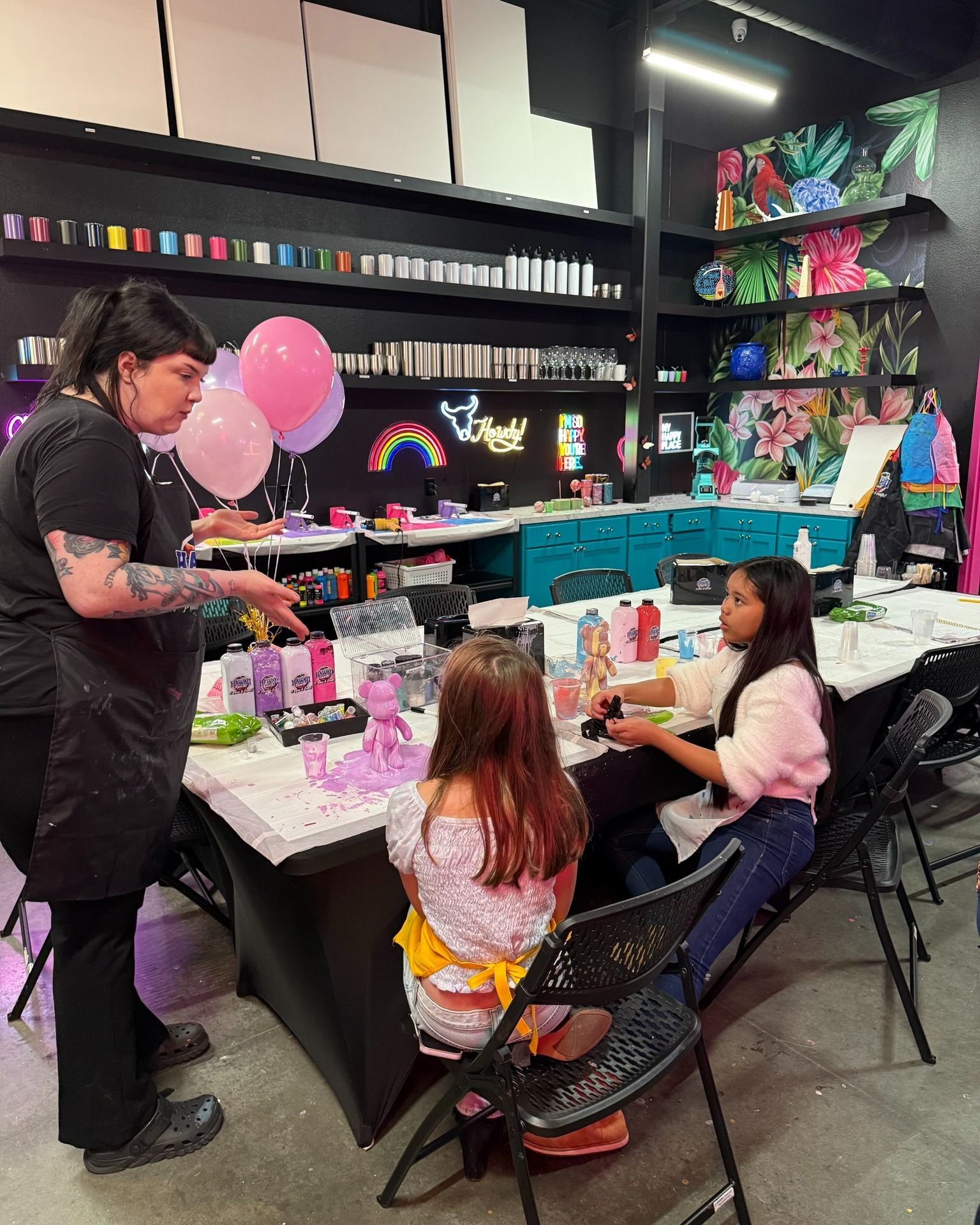 Birthday party setup with balloon decorations, gifts, and children seated at a decorated table