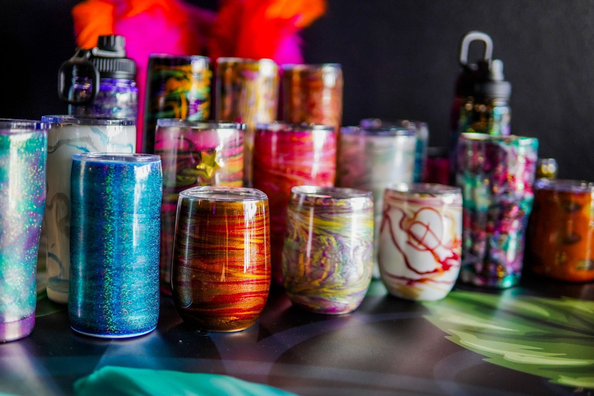 Colorful handmade glass candle holders and jars arranged on a table in bright light.