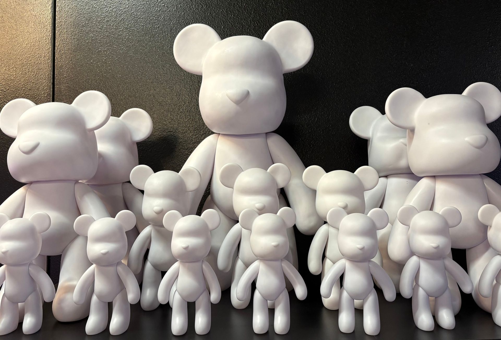 White bear figurines arranged in rows on a dark background, with large figures behind smaller ones
