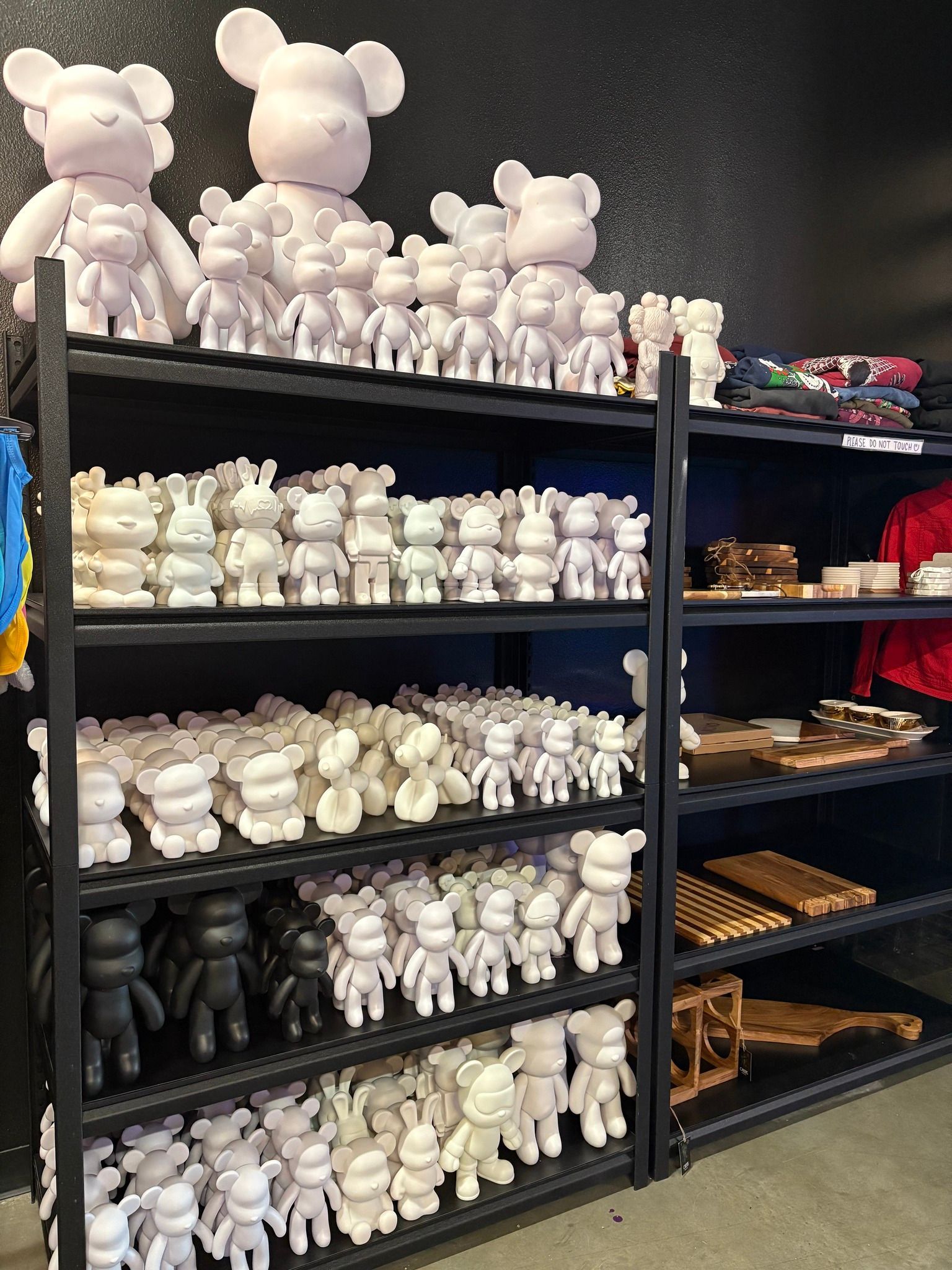 Shelves of white teddy bear figurines in a store display, with small colorful items on the right.