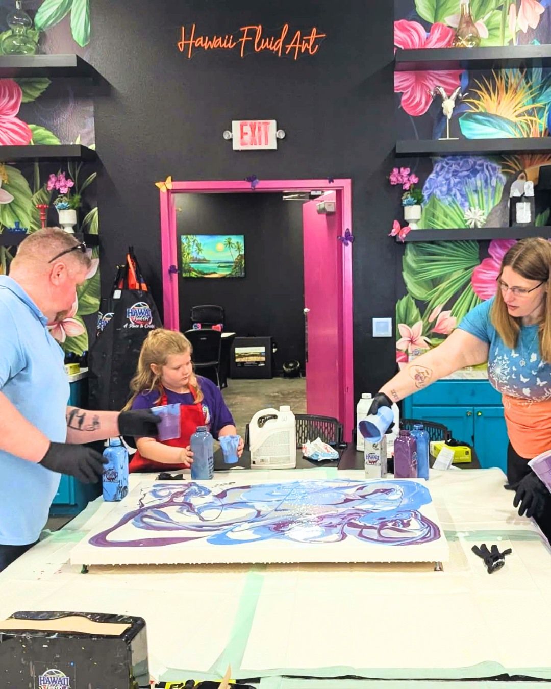 People painting a large artwork at a colorful art studio table