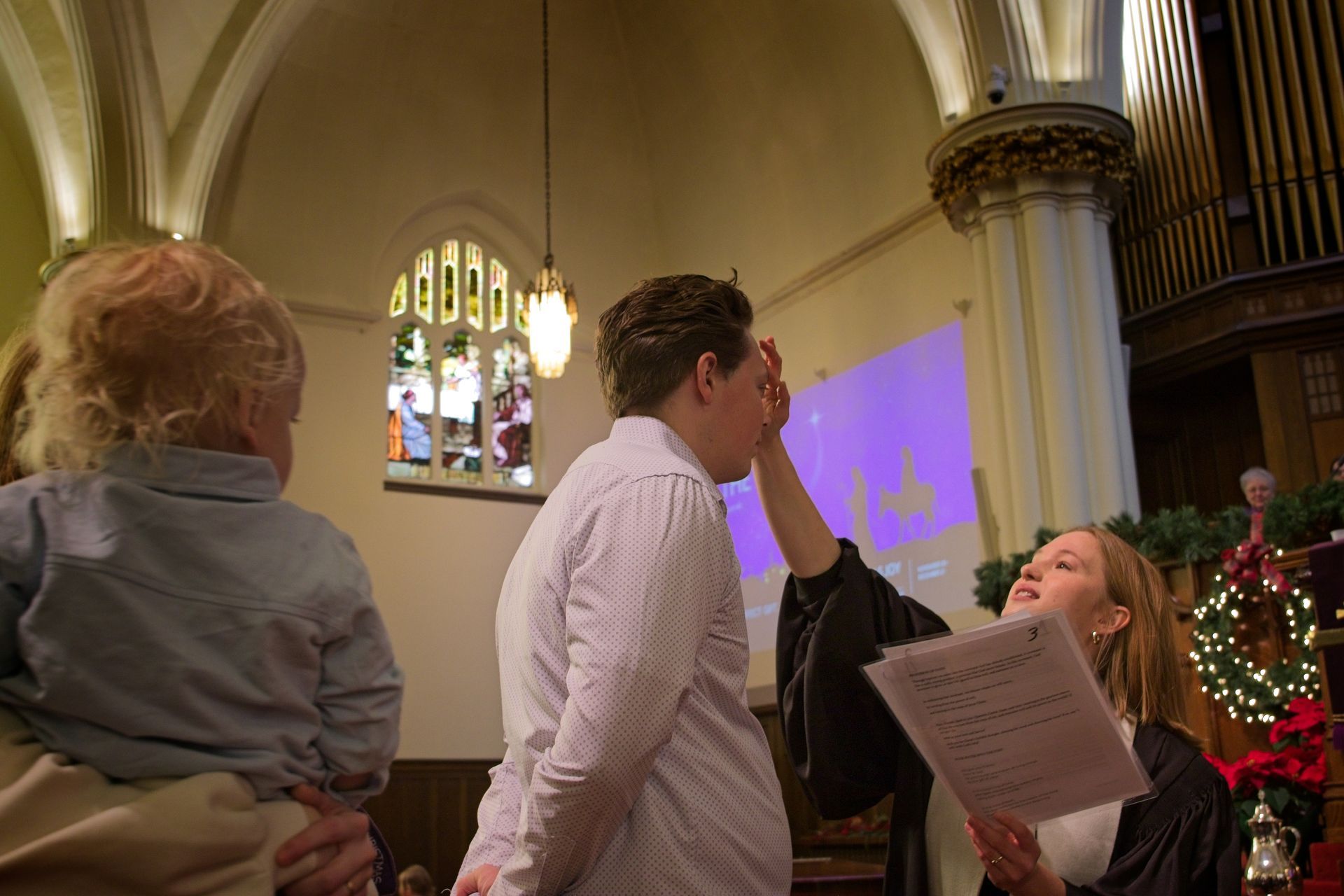 People singing in a church, with a child and a projected blue light on the wall