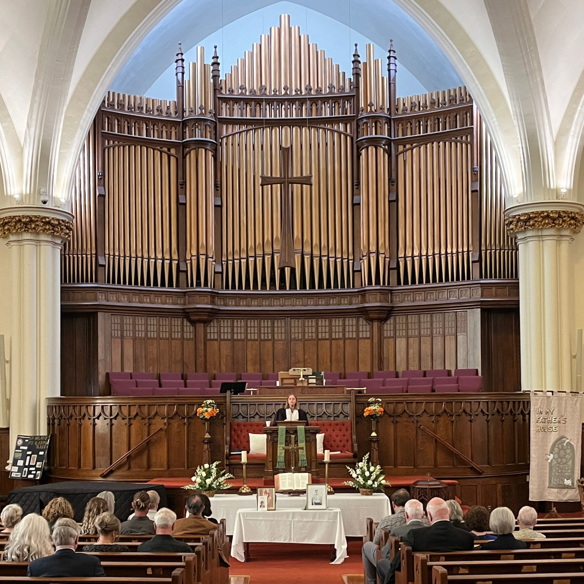 Church sanctuary with large pipe organ behind a congregation seated for a service
