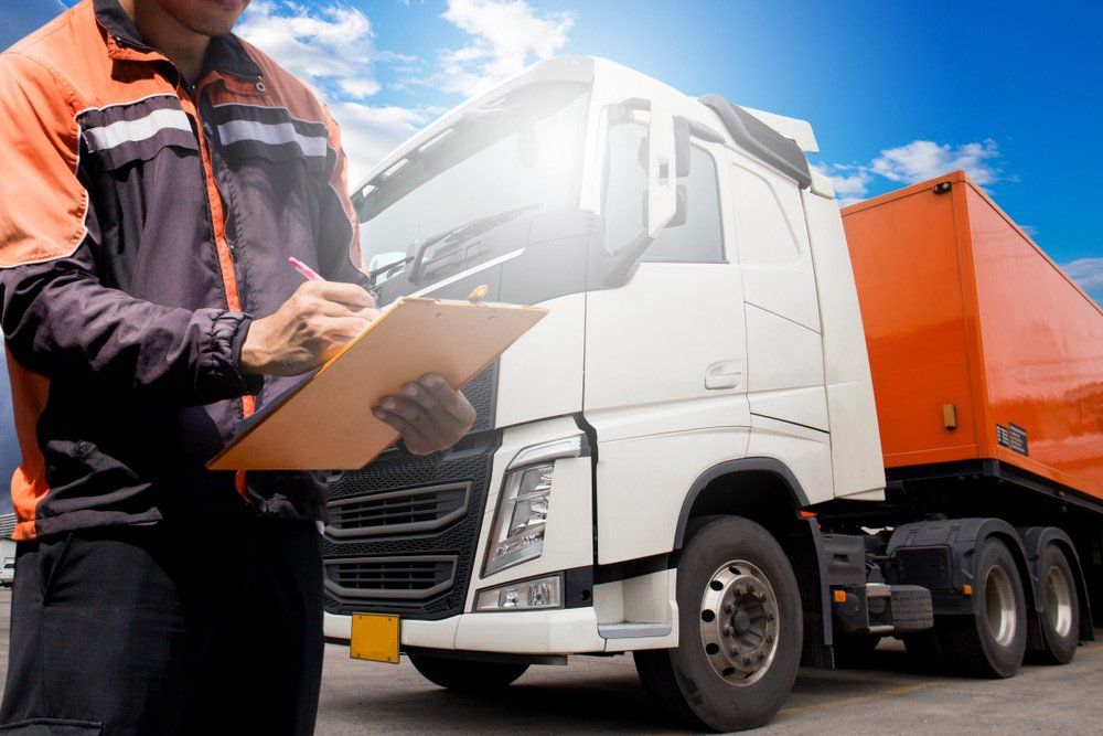 A Man is Writing on a Clipboard in Front of a Truck — Ceely's Heavy Vehicle Driver Training & Assessments In Cowra, NSW