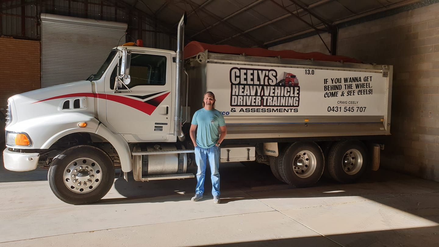 Man With Long Hair Standing Confidently Beside a Truck — Ceely's Heavy Vehicle Driver Training & Assessments In Albury, NSW 