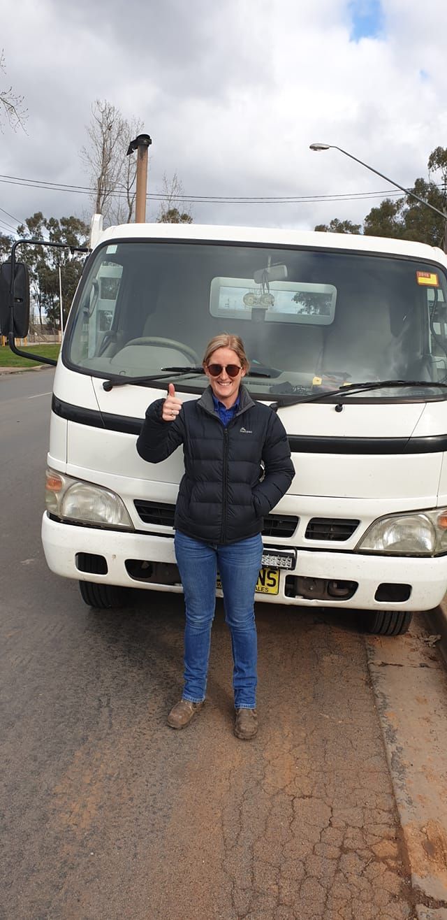 Lady Wearing Glasses With a Truck Behind Her — Ceely's Heavy Vehicle Driver Training & Assessments In Albury, NSW 