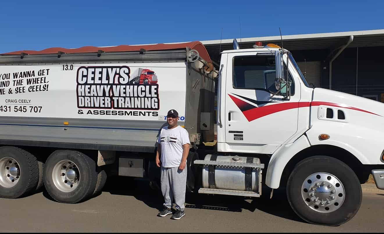 A Man is Standing in Front of a Vehicle Driver Training Truck — Ceely's Heavy Vehicle Driver Training & Assessments In Yass, NSW