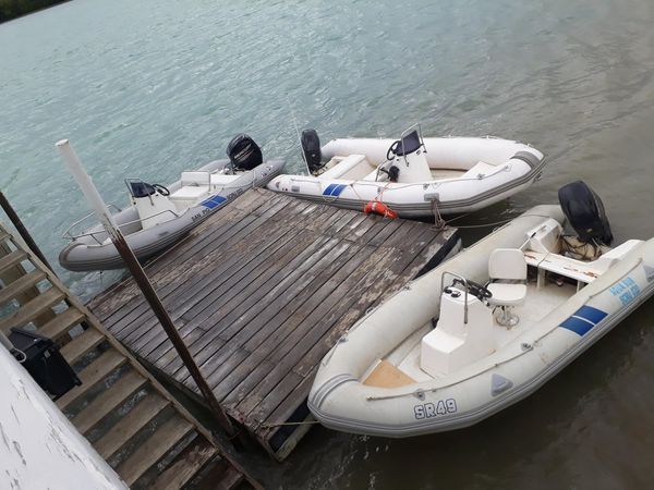 Tres barcos inflables atracados en un muelle de madera junto al agua.