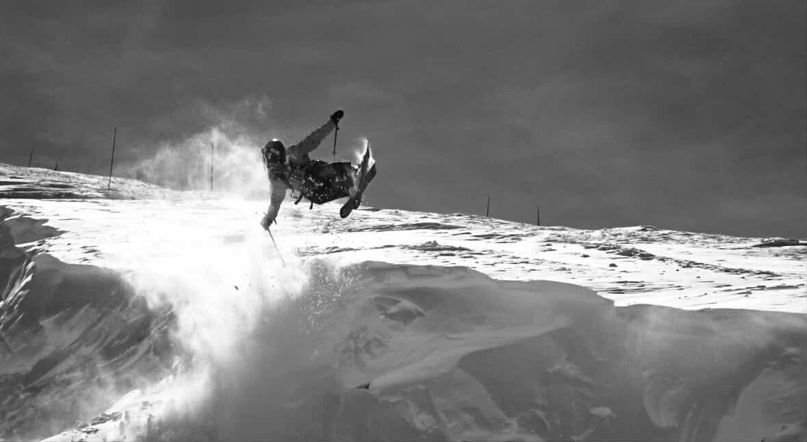 Surfer airborne above a breaking wave, with spray and ocean horizon in black and white