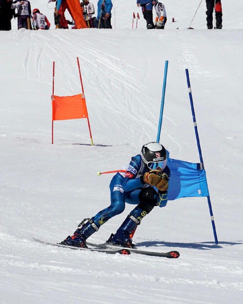 Skier in blue racing through slalom gates on a snowy slope