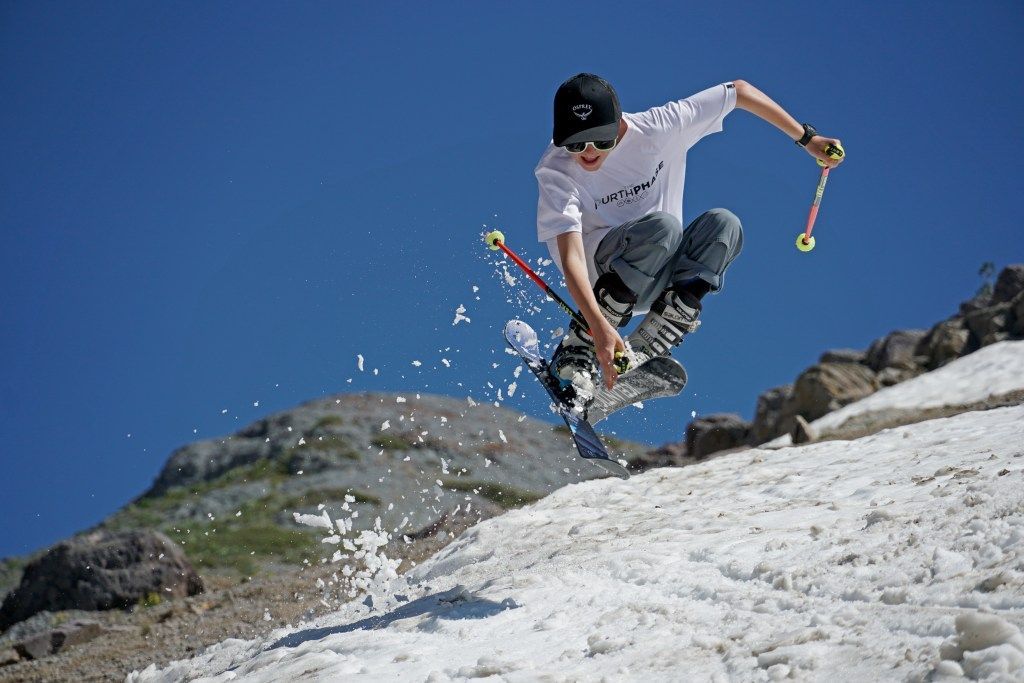 Snowboarder jumping over a snowy slope under a clear blue sky