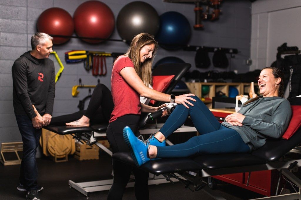 Physical therapy session with a trainer at PT Revolution stretching a patient on a treatment table in a gym clinic