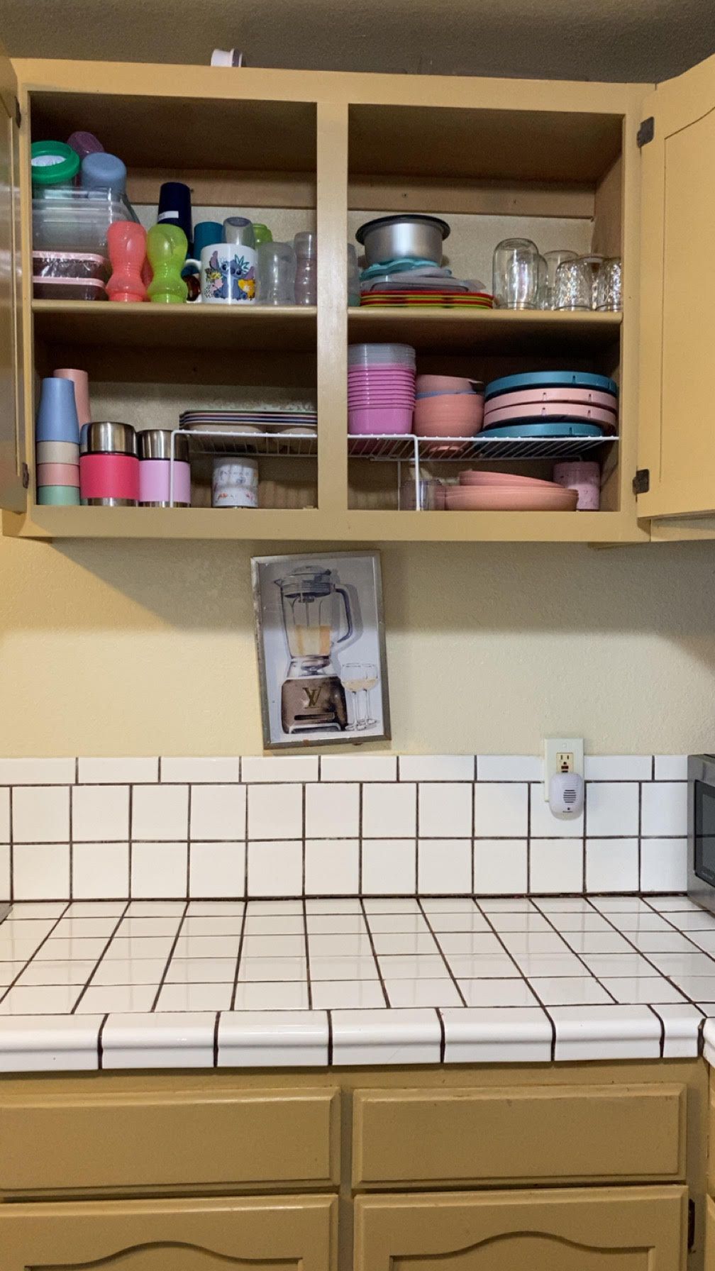 Kitchen cabinet open, revealing shelves of dishes, cups, and food storage containers. 