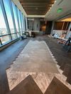 An interior construction space with unfinished herringbone wood flooring around a central, bare subfloor area.