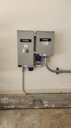 Two electrical boxes are hanging on a wall in a garage.