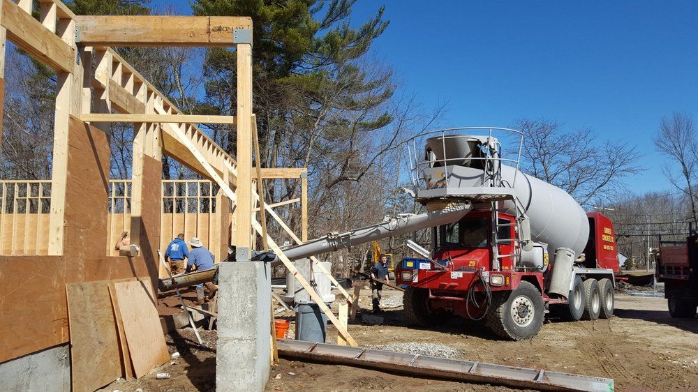 Construction site with a cement mixer truck pouring concrete into wooden forms for a foundation