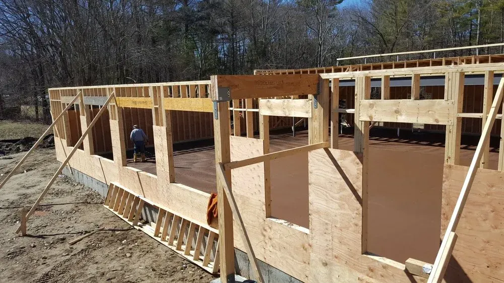 Wood-framed building under construction with plywood sheathing and one worker inside