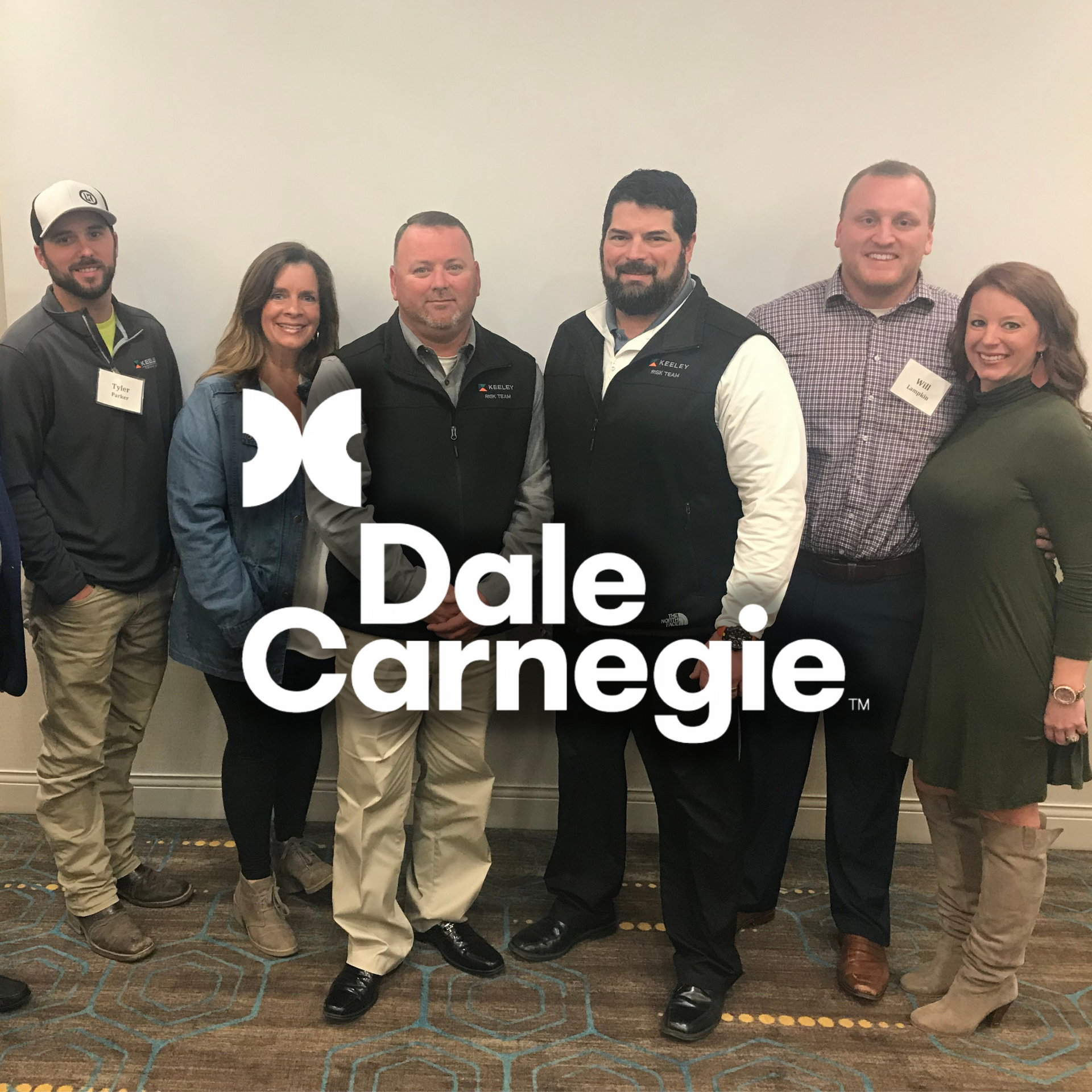 A group of people posing for a picture with the dale carnegie logo in the background