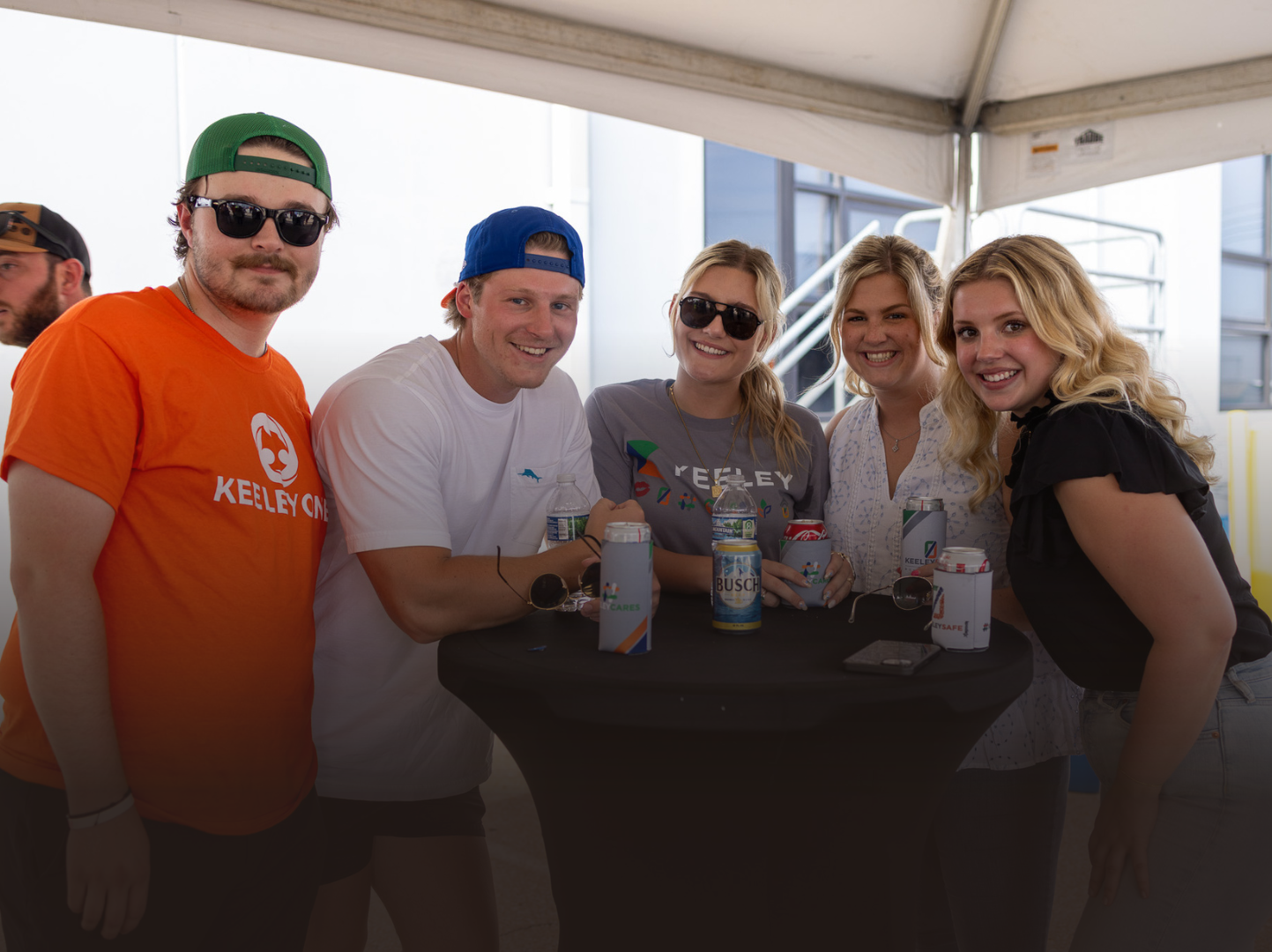 A group of people are standing around a table under a tent.