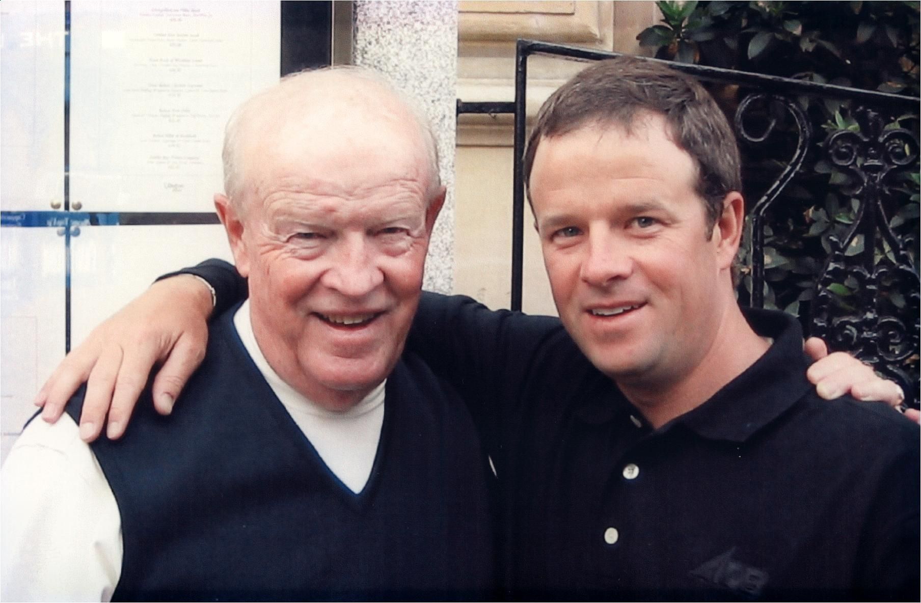 Two men are posing for a picture and one has his arm around the other 's shoulder