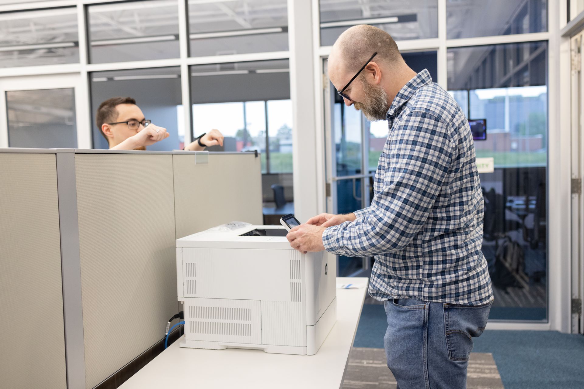 A man is standing in front of a printer in an office.