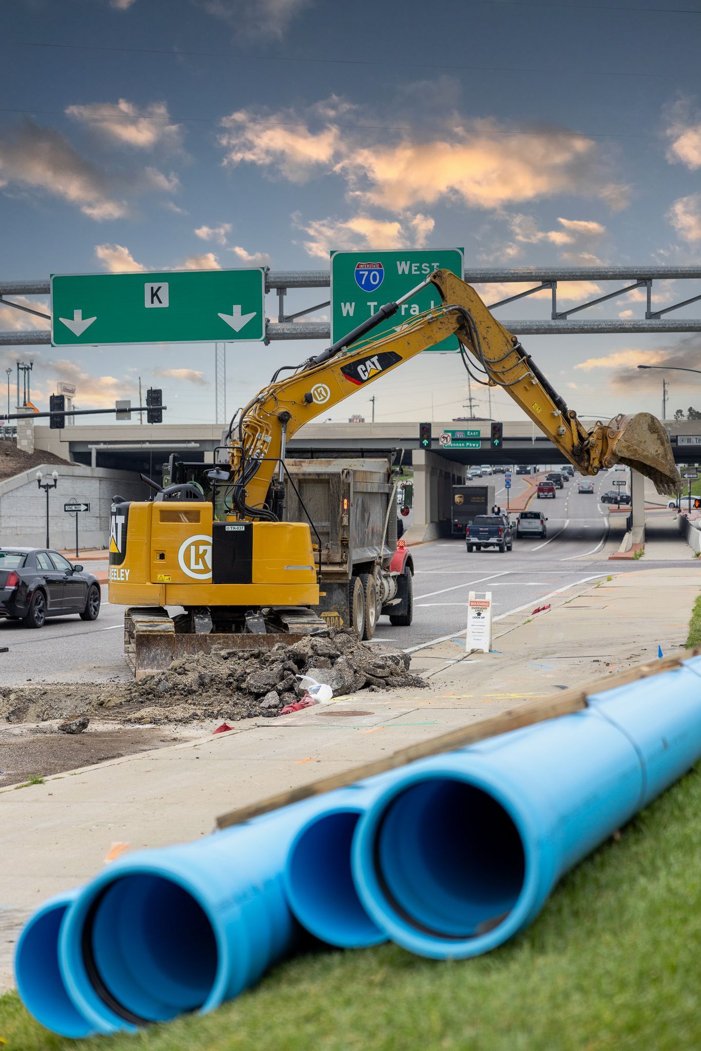 A construction site with a yellow excavator and blue pipes.