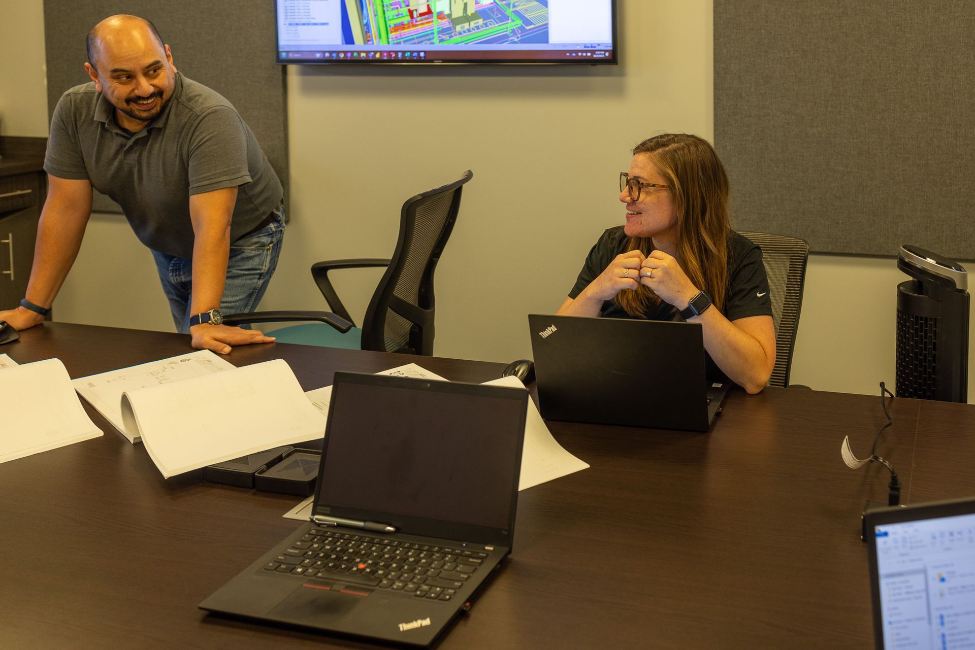 A man and a woman are sitting at a table with laptops.