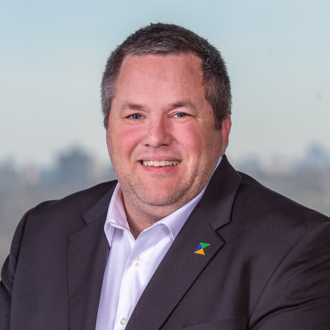 A man in a suit and white shirt is smiling for the camera.