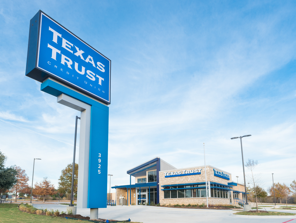 A large blue texas trust sign in front of a building