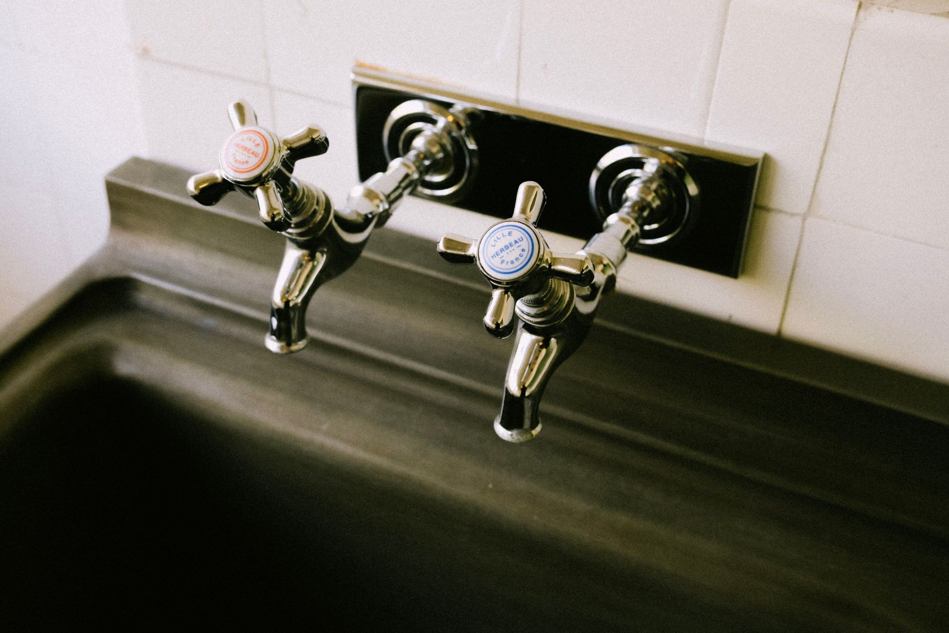 Two silver drinking fountains mounted on a wall above a stainless-steel basin