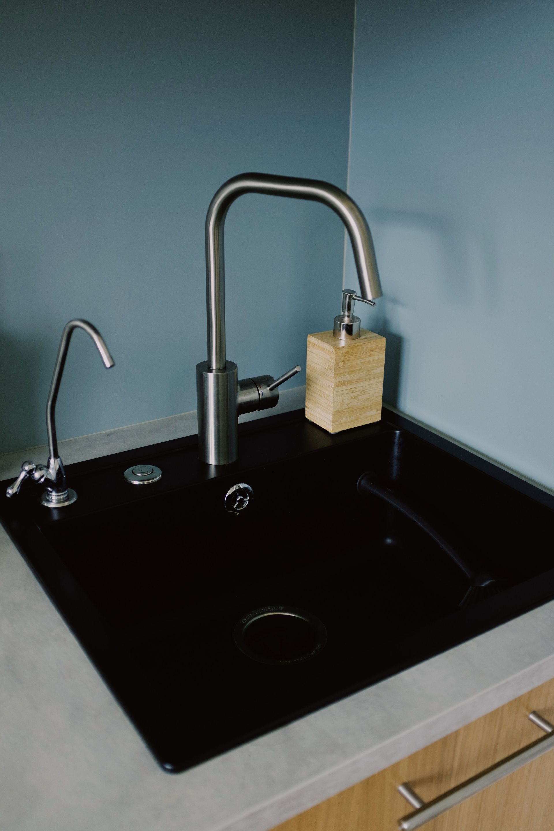 Black kitchen sink with a tall chrome faucet and a small padlock hanging from it.