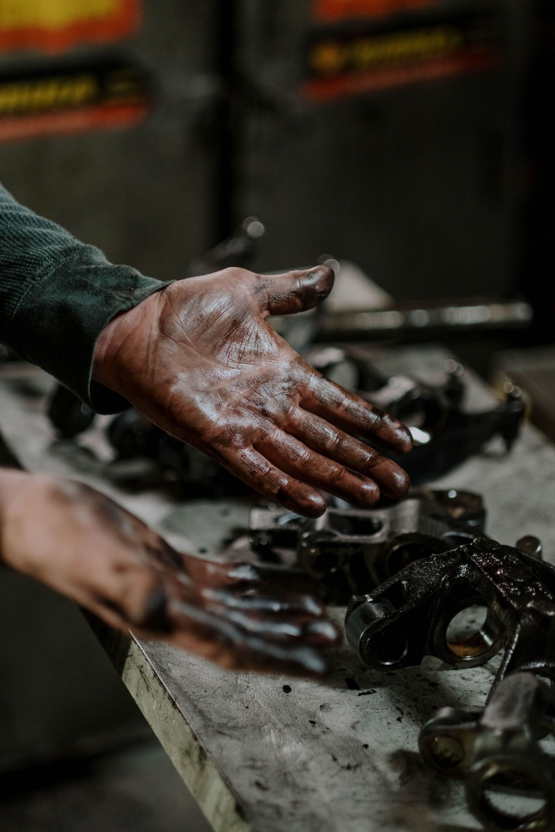 Oil-covered hands working on mechanical parts in a workshop