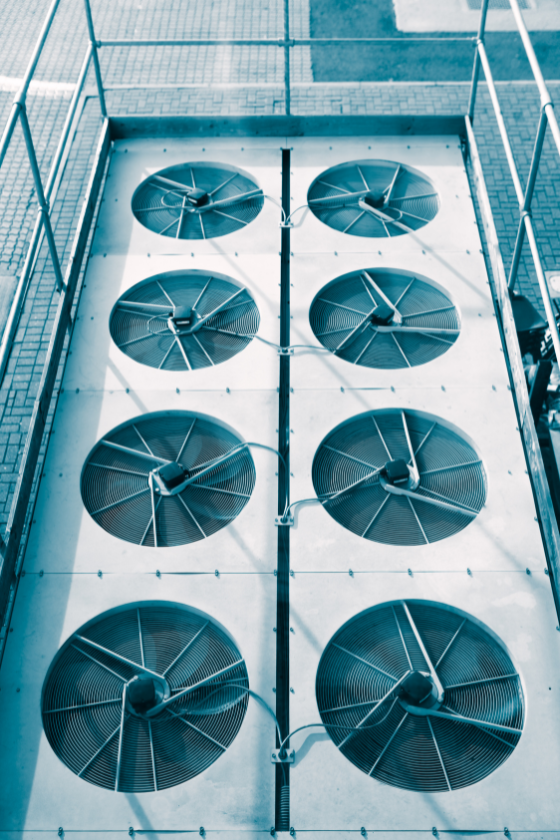 A row of fans are lined up in a row on top of a building.