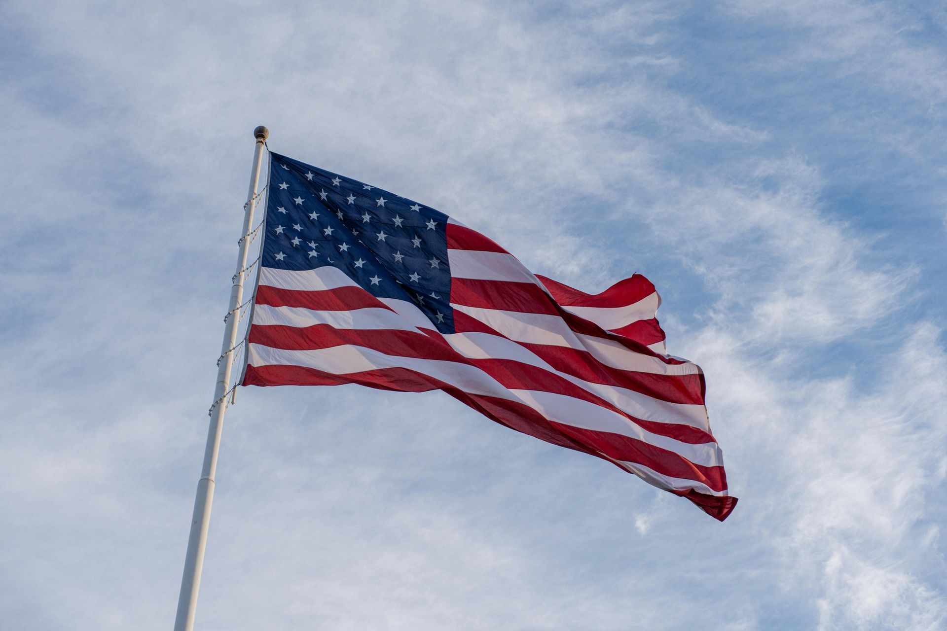 American flag waving on a pole against a cloudy sky