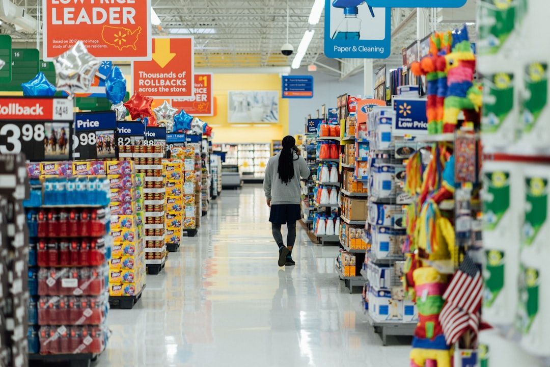 Person walking down an aisle in a Walmart store, surrounded by shelves of merchandise.