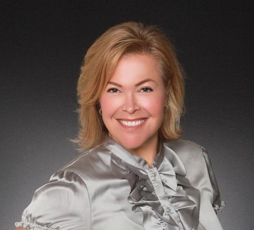 A woman in a satin blouse is smiling for the camera