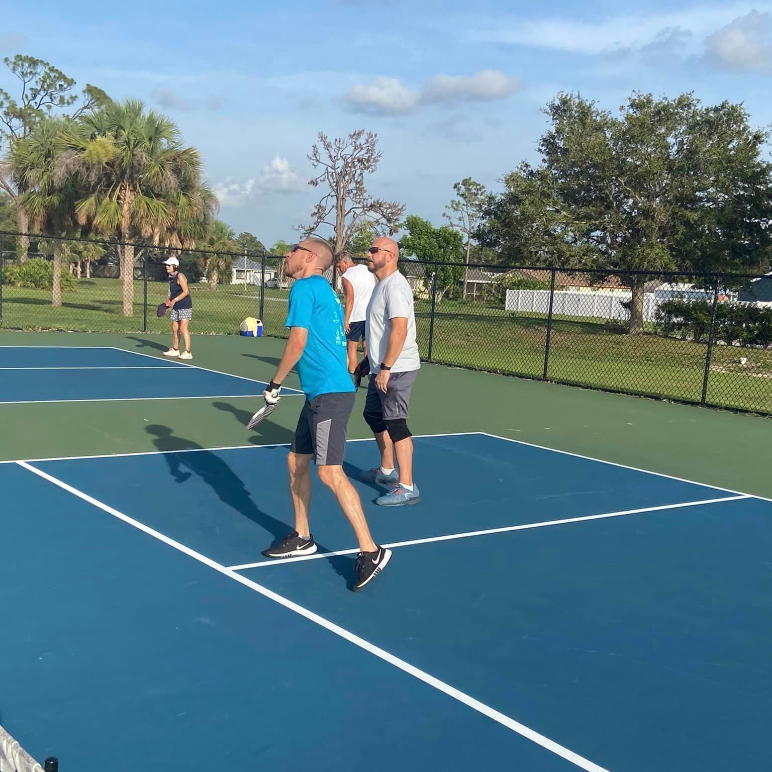A man in a blue shirt is holding a tennis racquet on a tennis court