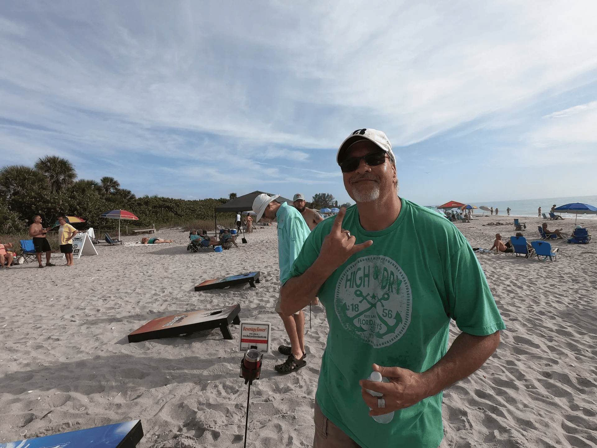 A man in a green shirt is standing on a beach.