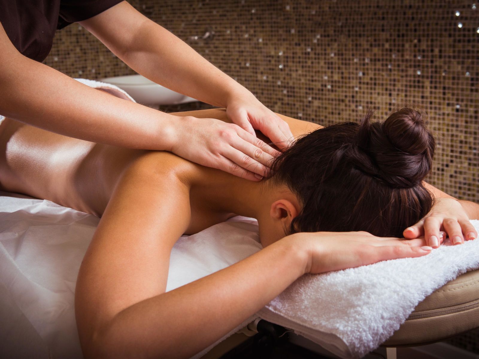 Woman receiving a back massage on a spa table with folded white towels