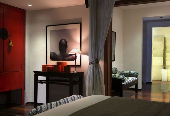 Modern bedroom with a bed, desk, lamp, curtain divider, and doorway to a lit hallway