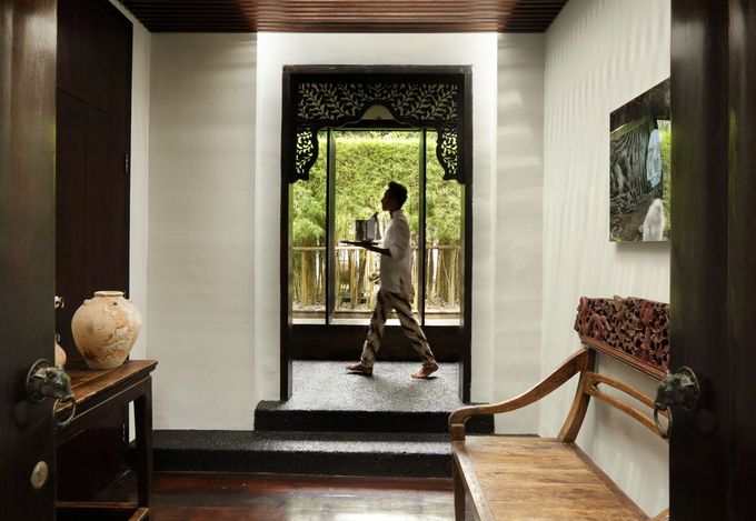 Person walking through a doorway in a bright hallway with wooden ceiling and bench seating