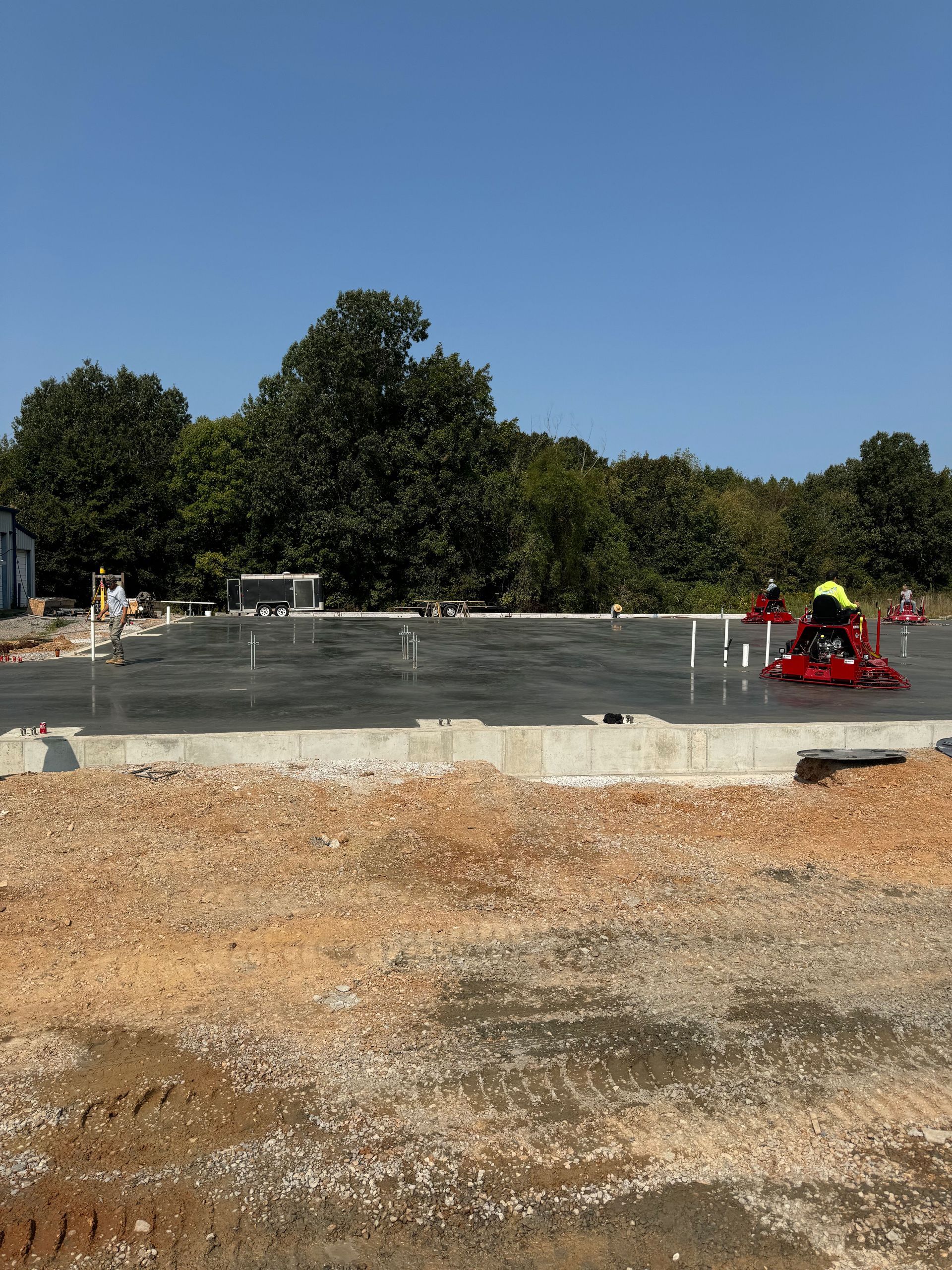 A construction site with a lot of dirt and trees in the background.