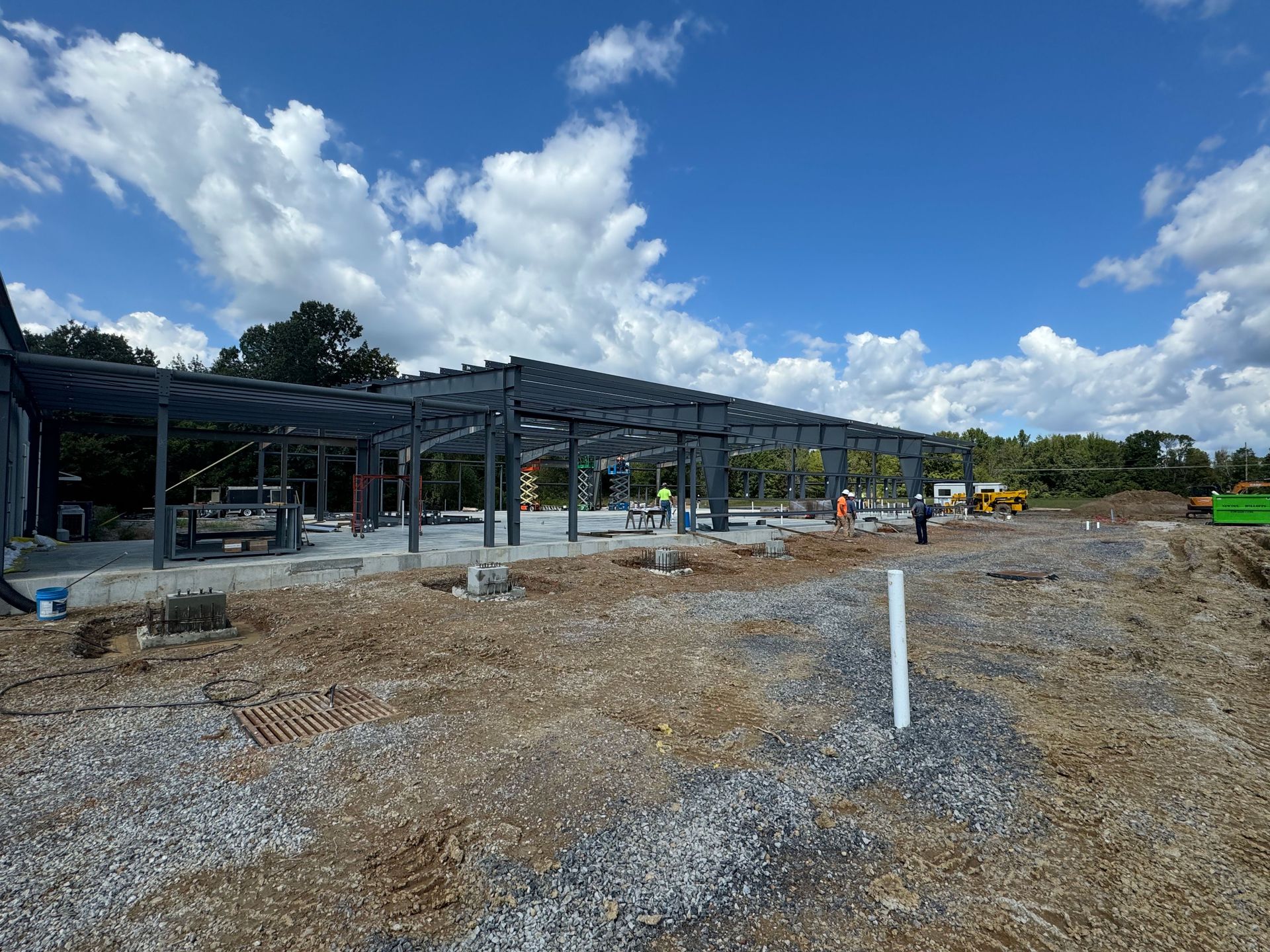 A large metal structure is being built in a dirt field.